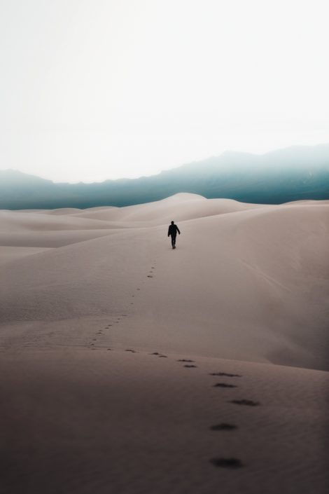 image of a person walking in the sand leaving a trail of footprints